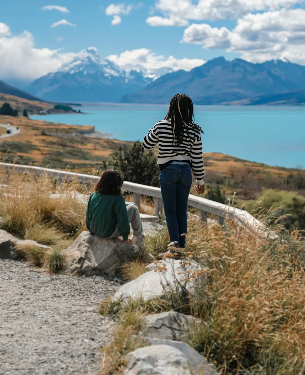 Two children standing at a lookout looking across New Zealand scenery of mountains and water